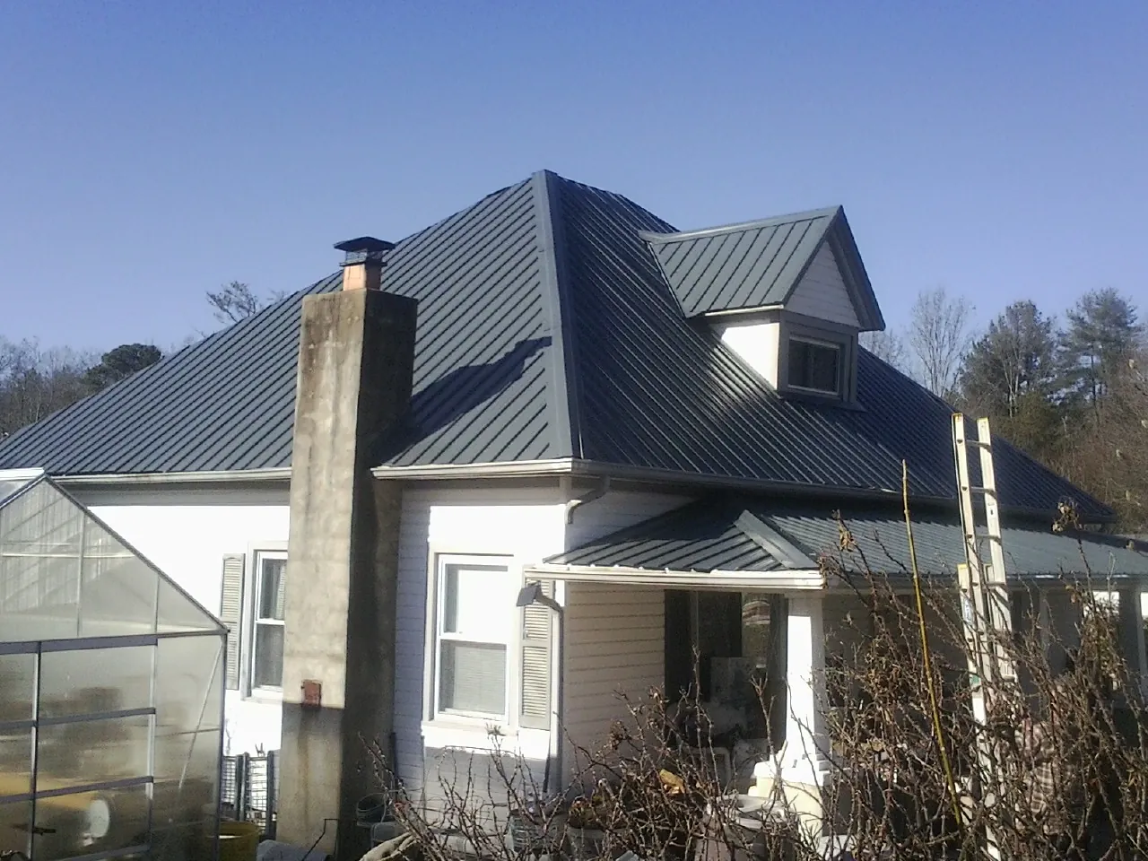 Dark blue standing seam metal roof on a white farmhouse with dormer — Slate & Tile Roof Repair by Roofing Brothers in Tarrs