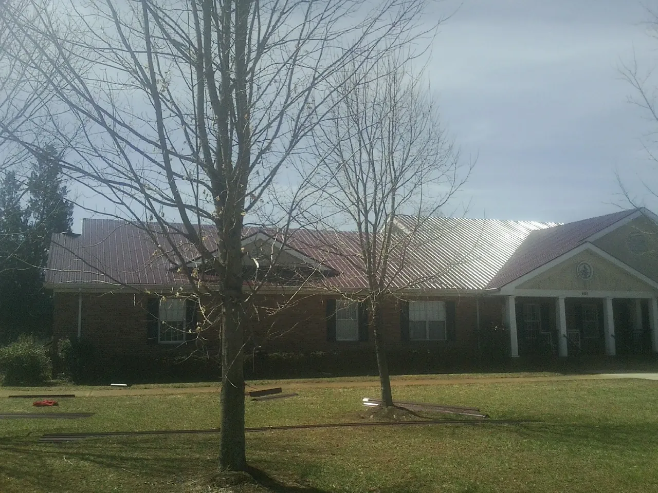 Red metal roof on a brick building seen from the front lawn in Tarrs