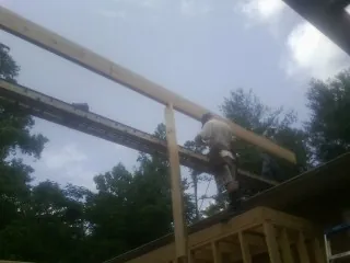 Carpenter setting a ridge beam over a new addition frame — Ice Dam Removal by Roofing Brothers in Tarrs