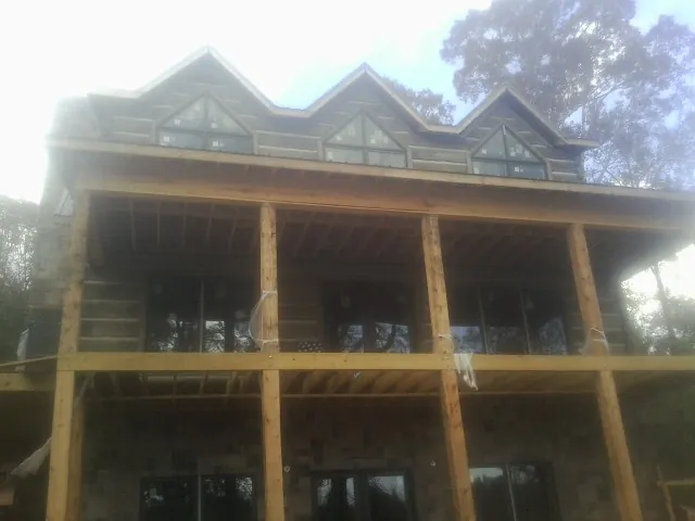 Dormers and porch framing on a large log home under construction — Roof Coating work by our crew in Tarrs