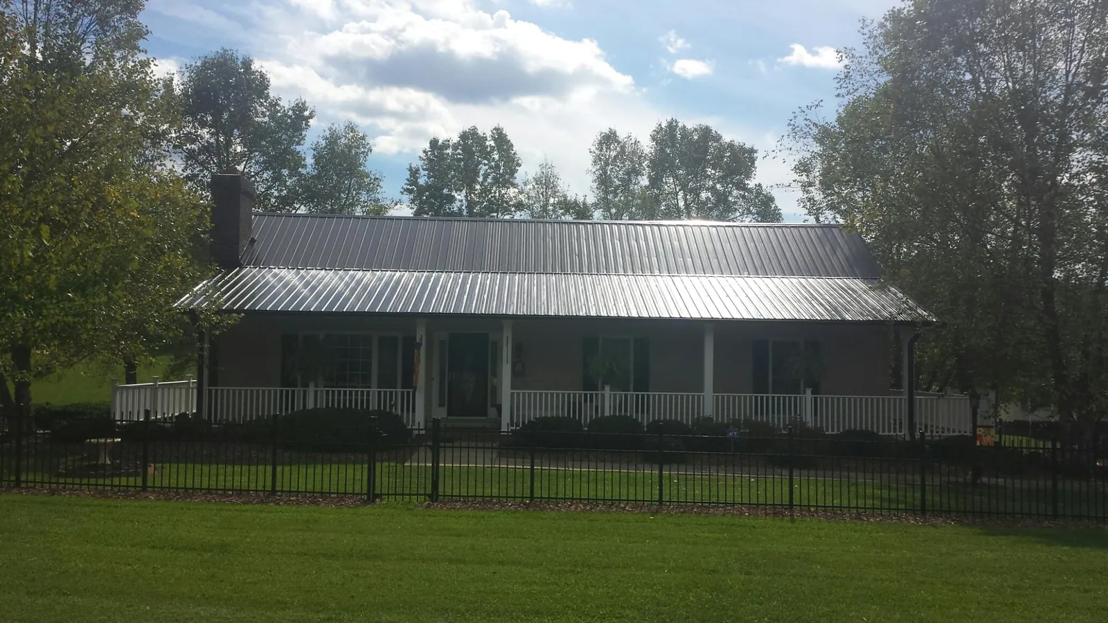 Gray metal roof on a brick ranch with a full width front porch — Gutter Guard Installation work by our crew in Tarrs
